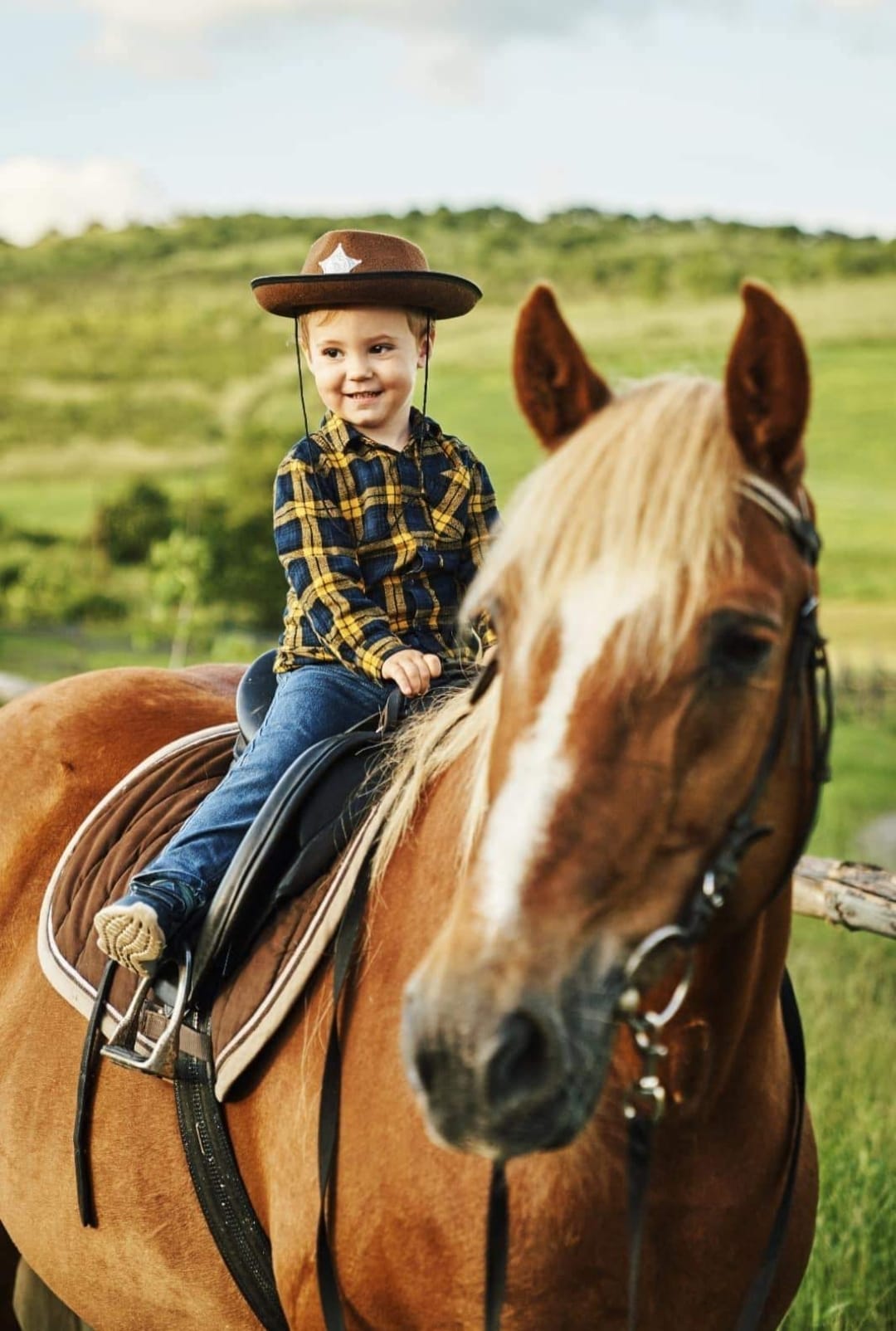 Copil cu pălărie de cowboy călare pe cal