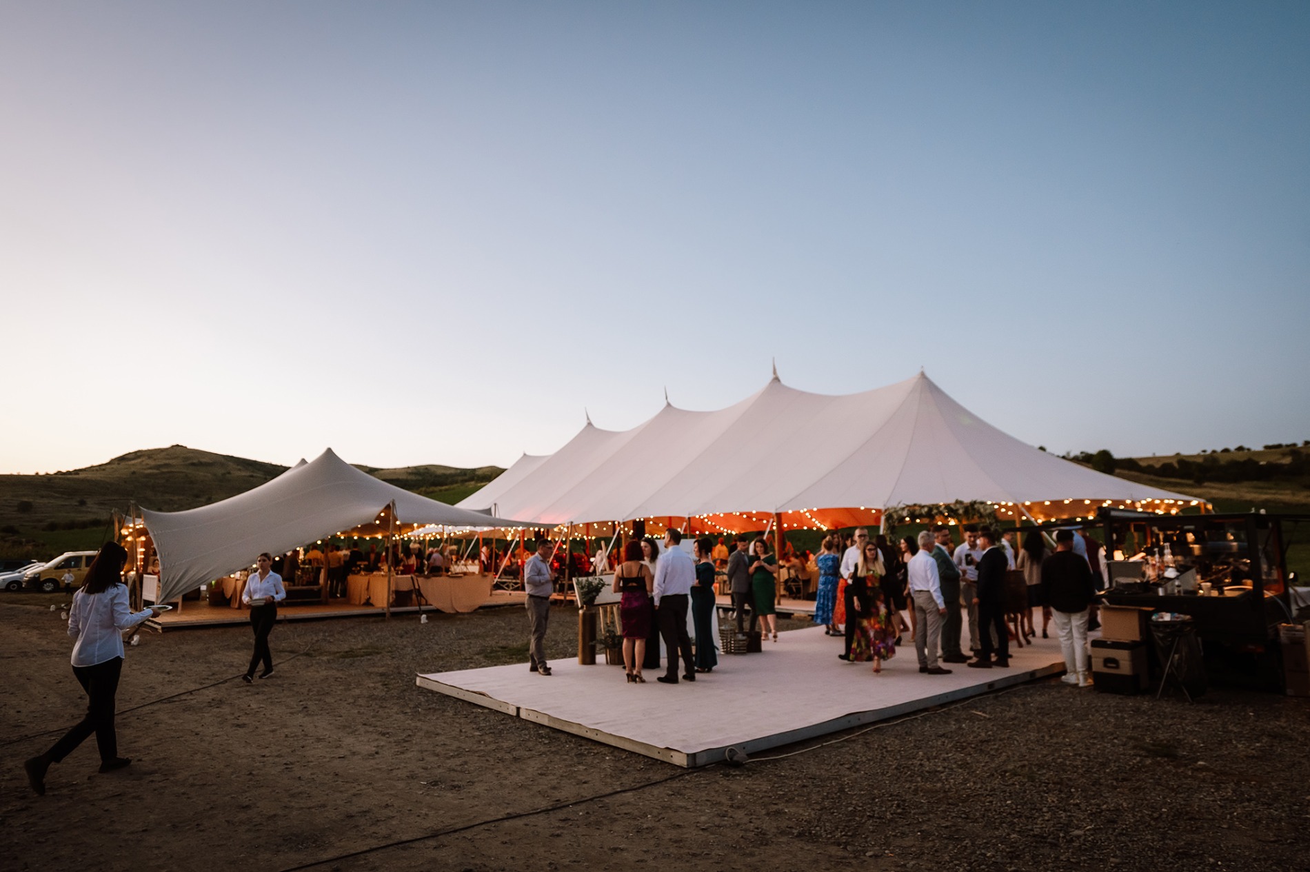 Cort de eveniment iluminat, cu invitați, la asfințit